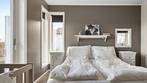 A bedroom with a large bed, two bedside tables, a window with blinds, and a wall-mounted shelf with a picture. - Large villa in Lofoten with fantastic views! (Stamsund)