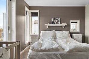 Una camera da letto con un letto grande, due comodini, una finestra con persiane e una mensola a parete con un quadro.