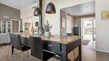 Een moderne keuken met een houten eiland, zwarte stoelen, hanglampen en uitzicht naar buiten.