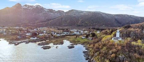 A coastal village with a church, houses, and mountains in the background.