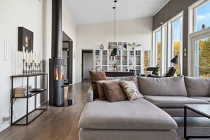 A modern living room with a sectional sofa, a fireplace, and a large window with a view of trees.