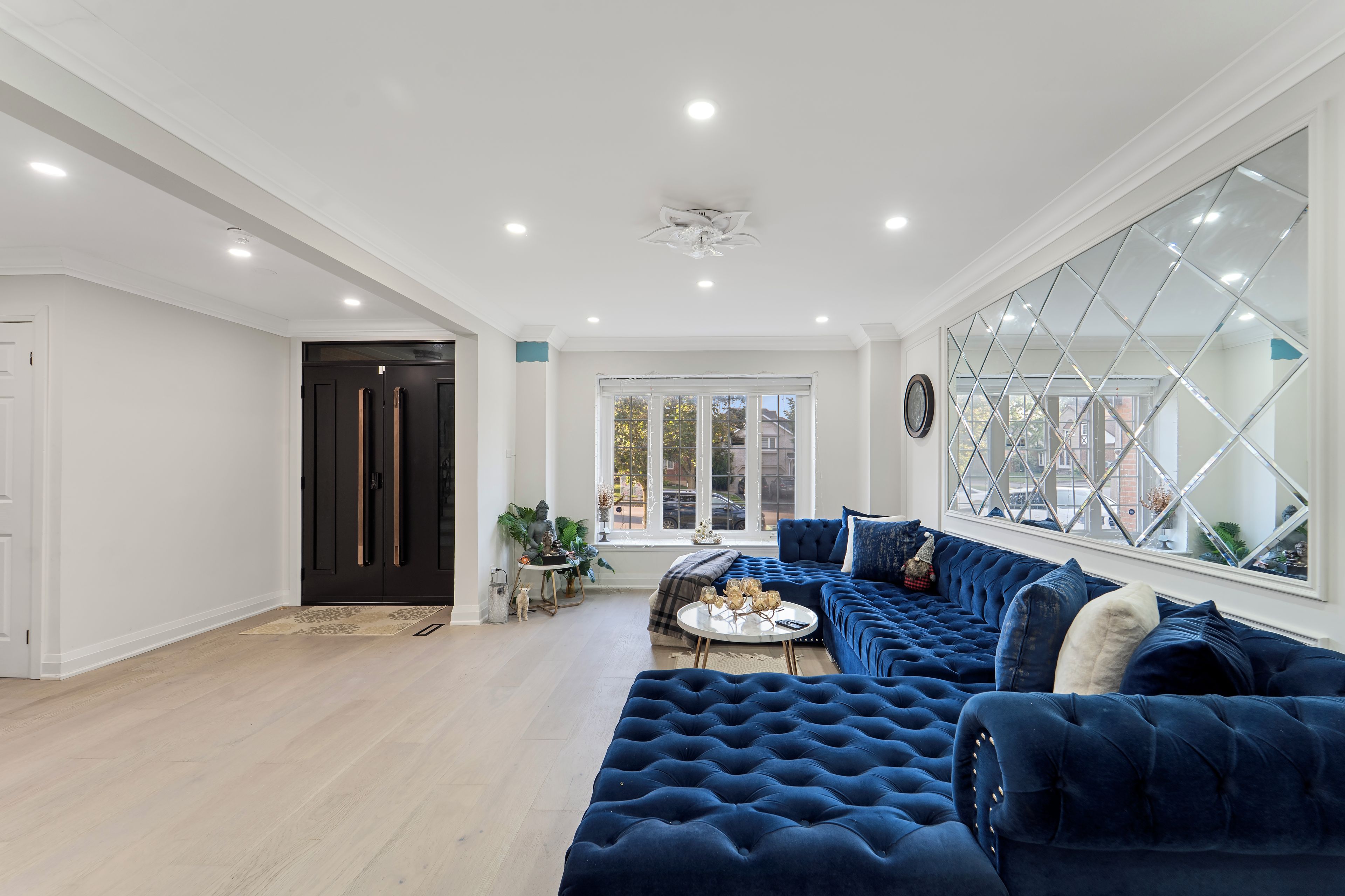 Un salon spacieux avec un grand canapé d’angle, une table basse et une vue dégagée sur l’extérieur grâce à une grande fenêtre.
