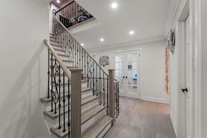 A staircase with wooden steps and black iron railings leading to a landing.