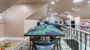 A dining area with a long table, chairs, and a railing.