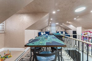 A dining area with a long table, chairs, and a railing.