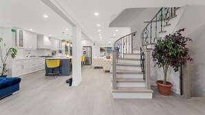 A modern kitchen with white cabinets, a central island, and a dining area with yellow chairs.