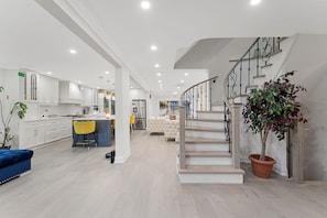 A modern kitchen with white cabinets, a central island, and a dining area with yellow chairs.