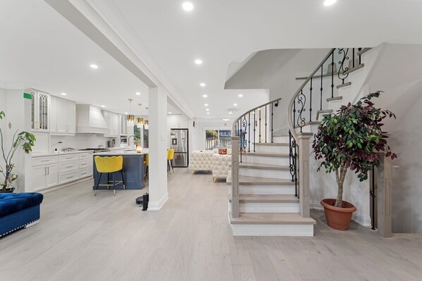 A modern kitchen with white cabinets, a central island, and a dining area with yellow chairs.