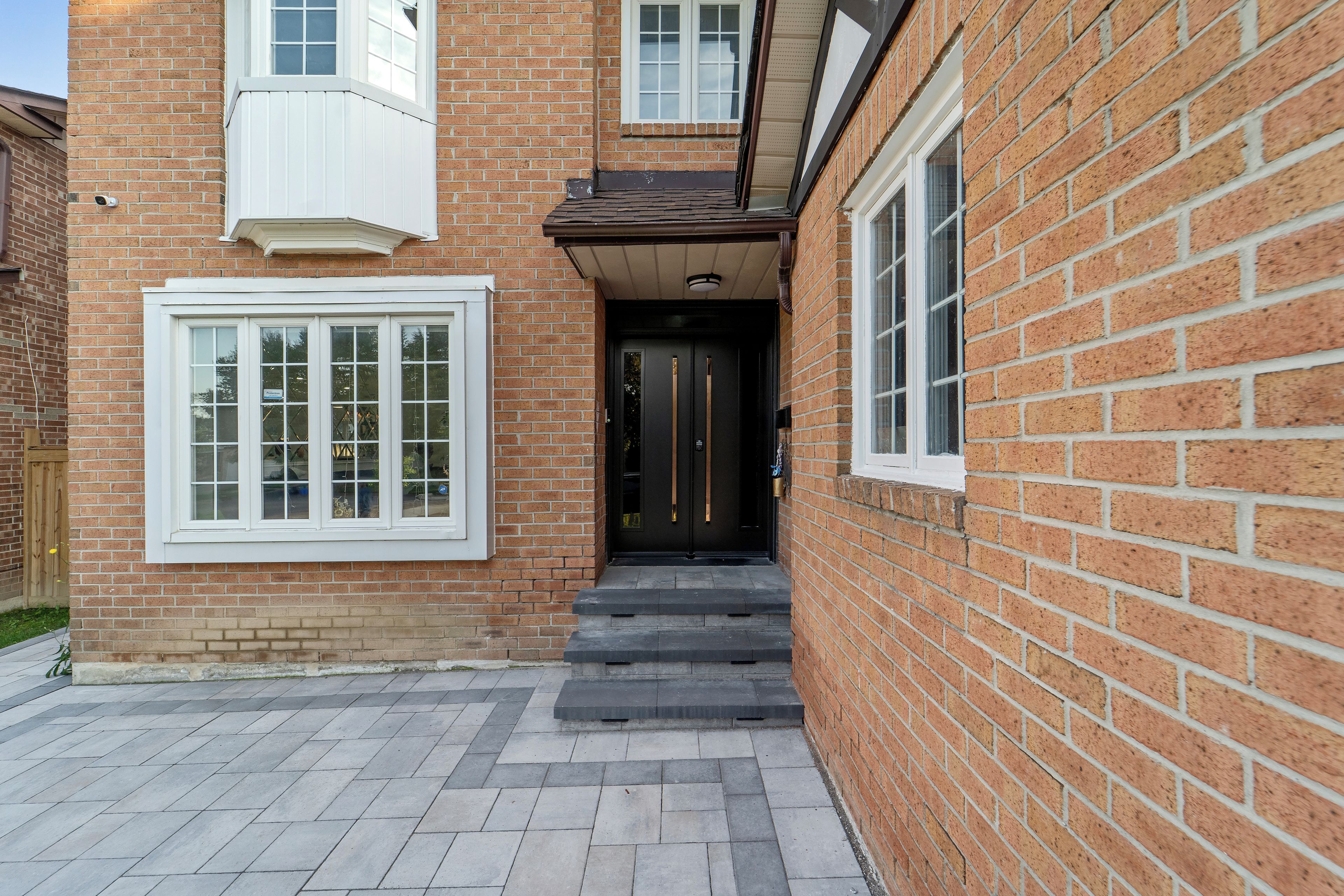 A brick building with a front door, a window with a white frame, and a small porch area.