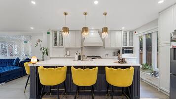 A modern kitchen with a central island, bar stools, pendant lights, and a built-in oven.