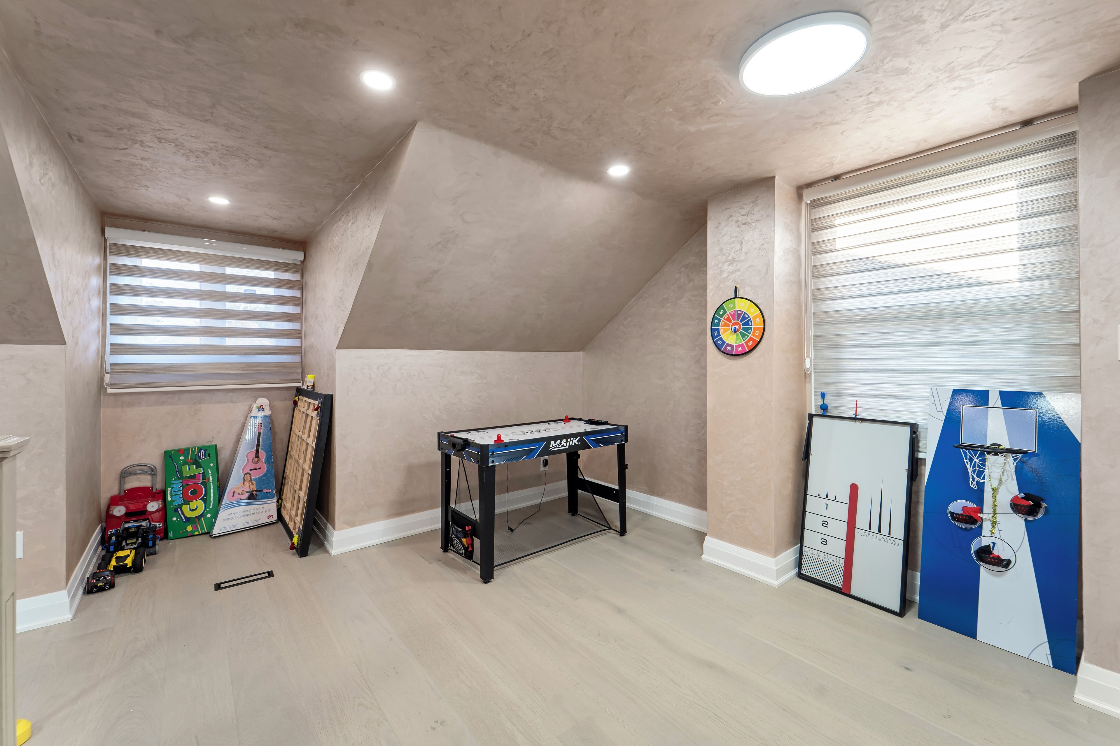 A room with a foosball table, a dartboard, and a mini-golf setup.