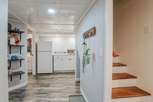 Un pasillo con cocina, estanterías de madera y una escalera.