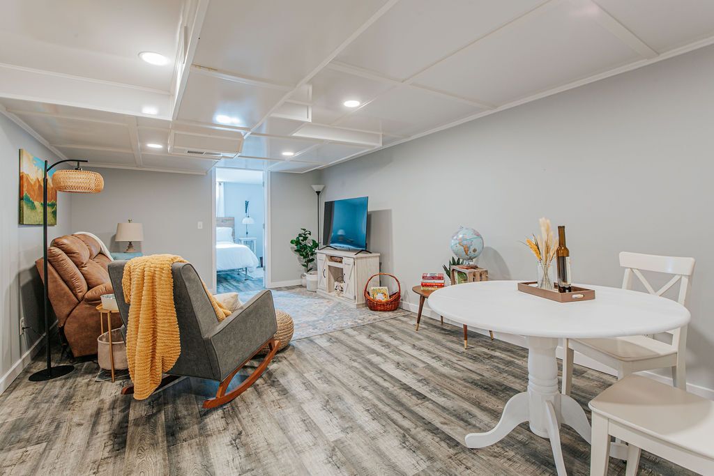 Uma sala de estar moderna com sofá, poltrona, mesa redonda e televisão.