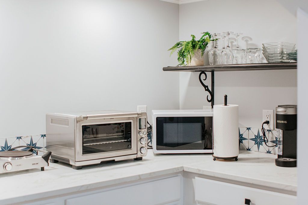 Uma cozinha com forno elétrico, micro-ondas e máquina de café no balcão.