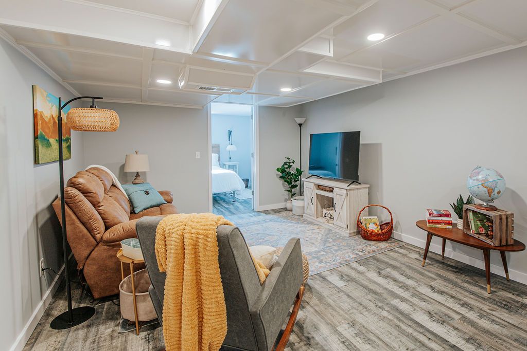 A modern living room with a sofa, armchair, TV, and a bookshelf.