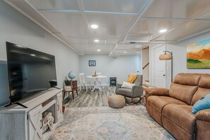 A living room with a flat-screen TV, a brown leather sofa, a patterned rug, a small round table, and a white wall with a framed picture. - Blue Ridge Hideaway (Waynesboro)