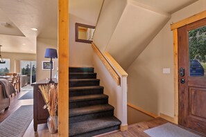 Un escalier avec des rampes en bois et des marches recouvertes de moquette, menant à l’étage supérieur.