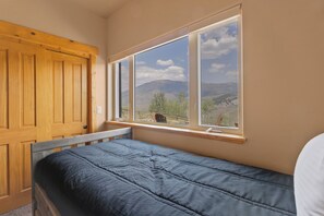 A bedroom with a single bed, a wooden wardrobe, and a window with a mountain view. - Secluded private home with incredible views (Silverthorne)