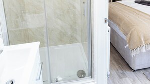 Et moderne badeværelse med en glasafskærmet brusekabine, et kontrolpanel og et synligt toilet.