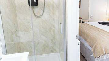 A modern bathroom with a glass-enclosed shower, a control panel, and a visible toilet.