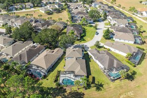 A residential area with houses featuring sloped roofs, solar panels, and swimming pools. - Bright & Spacious 6BR Near Disney w/Pool (Davenport)