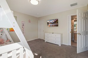 A child's room with a crib, a dresser, and a wall-mounted TV. - Bright & Spacious 6BR Near Disney w/Pool (Davenport)