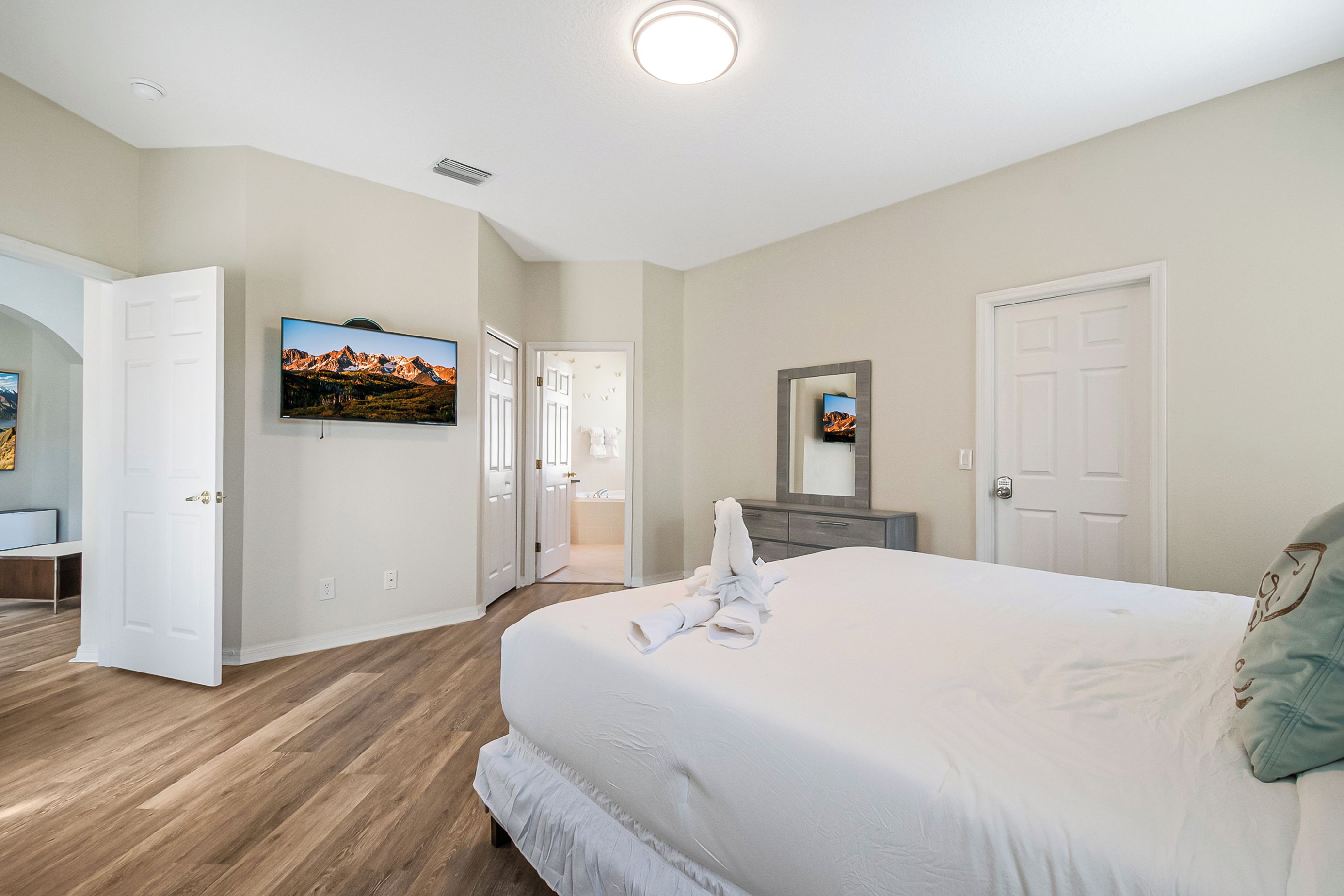 Habitación de hotel con una cama grande, televisión, baño y puerta que da a otra habitación.