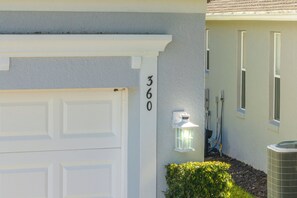 A residential garage with a white door, a mailbox with the number 360, and a small white lantern on the wall. - Bright & Spacious 6BR Near Disney w/Pool (Davenport)