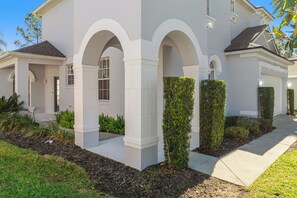 A modern house with a white exterior, arched windows, and a well-maintained garden. - Bright & Spacious 6BR Near Disney w/Pool (Davenport)
