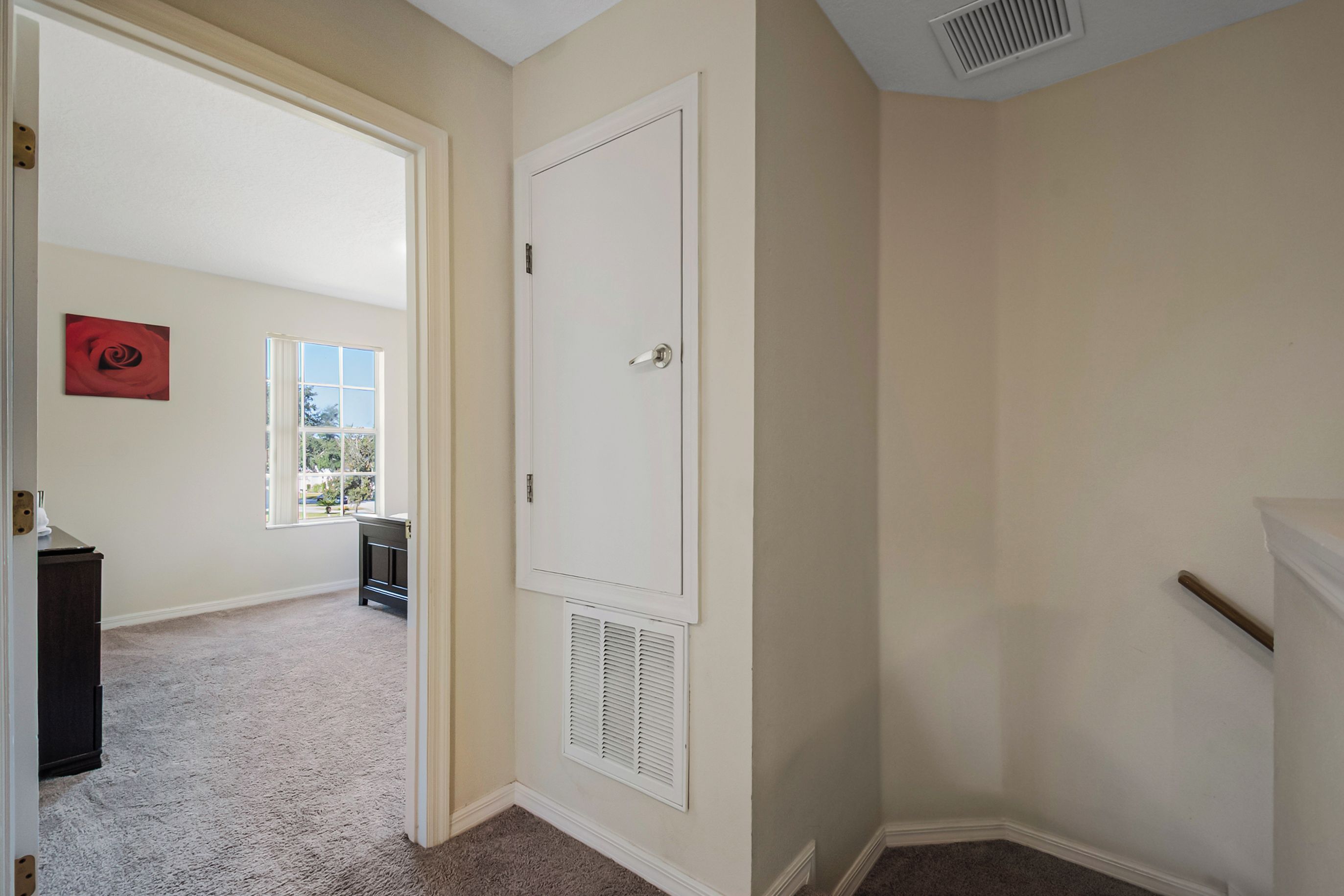 Un pasillo con una puerta, un radiador y una ventana que da al exterior.