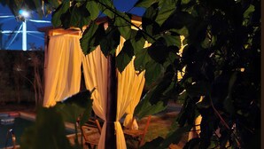 A tree with draped fabric, possibly for decoration, in a nighttime setting.