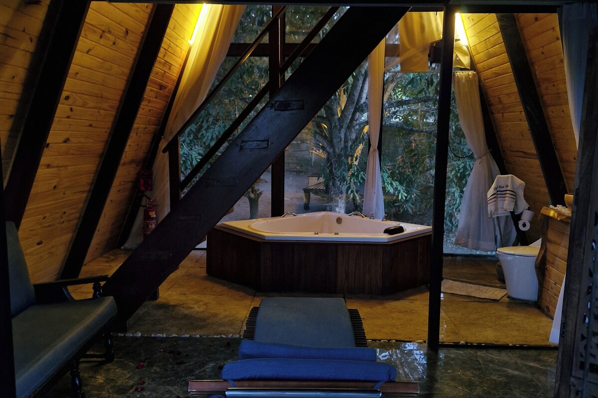 Un espacio de spa con una bañera de hidromasaje, bancos de madera y suelo de piedra.