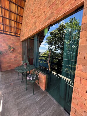 Un patio con un muro de ladrillo, una puerta de cristal y una mesa con sillas.