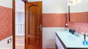Une salle de bain avec une porte en bois, un lavabo avec un miroir et des carreaux décorés.