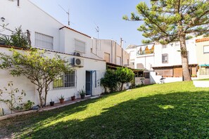 A residential area with white buildings, a small garden, and a tree.