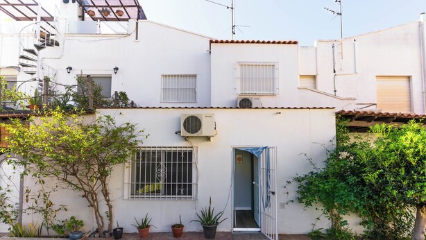Un immeuble résidentiel à la façade blanche, doté d’un petit jardin devant et d’une porte donnant sur l’entrée.