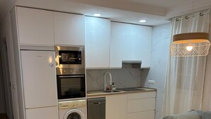 A compact kitchen with built-in appliances, a dining area with a round table and chairs, and a hanging light fixture. - Spacious Apartment in Moncloa, Madrid (Madrid)