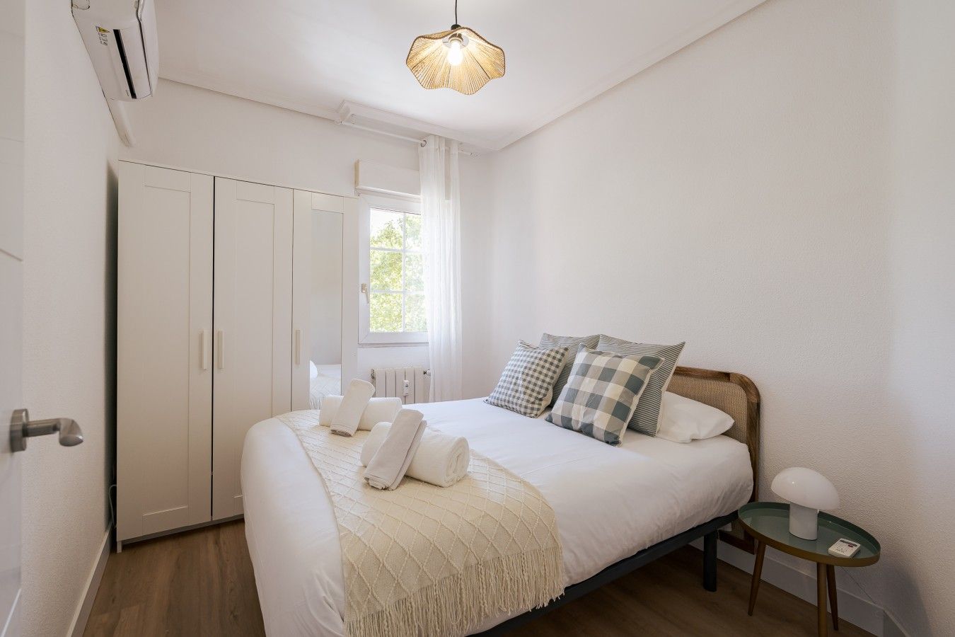 Un dormitorio con cama, mesita de noche, armario y ventana.
