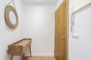 A hallway with a wooden bench, a wooden door, and a wall-mounted light fixture.
