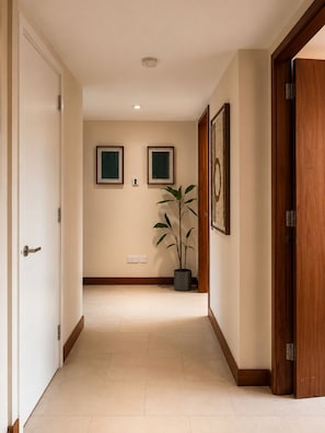 A hallway with a potted plant, two framed artworks, and a wooden door. - Luxury Marylebone Penthouse (London)