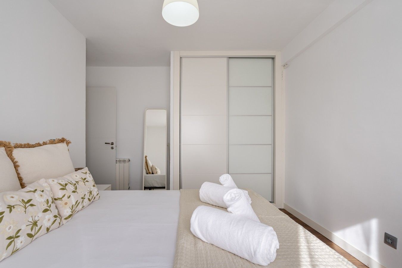 Un dormitorio con una cama, una mesita de noche, un espejo y una toalla en el suelo.