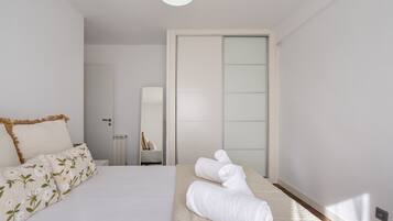 Une chambre à coucher avec un lit, une table de chevet, un miroir et une serviette sur le sol.