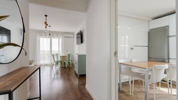 Une cuisine moderne avec des meubles blancs, un réfrigérateur en acier inoxydable et une table à manger en bois, accompagnée de chaises.