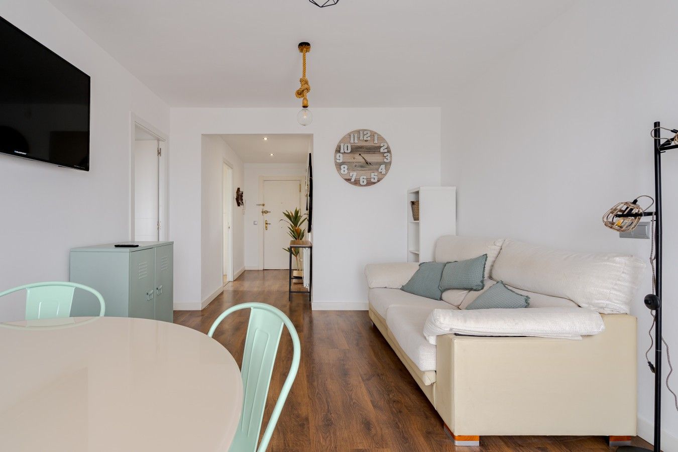 Ein modernes Wohnzimmer mit einer Couch, einem Esstisch und einem an der Wand befestigten Fernseher.