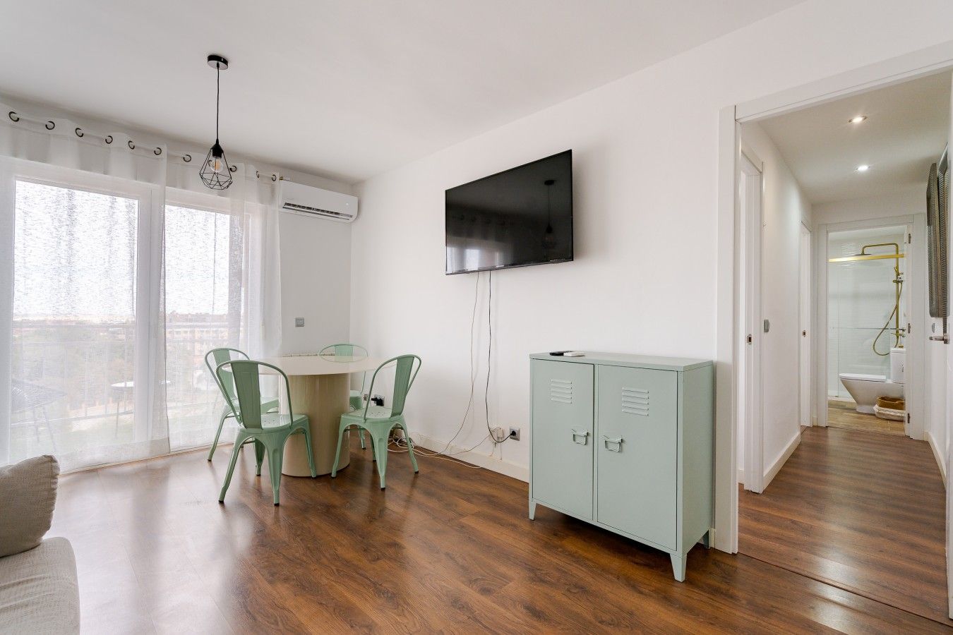 Una sala moderna con comedor, un televisor de pantalla plana montado en la pared y un vestidor.