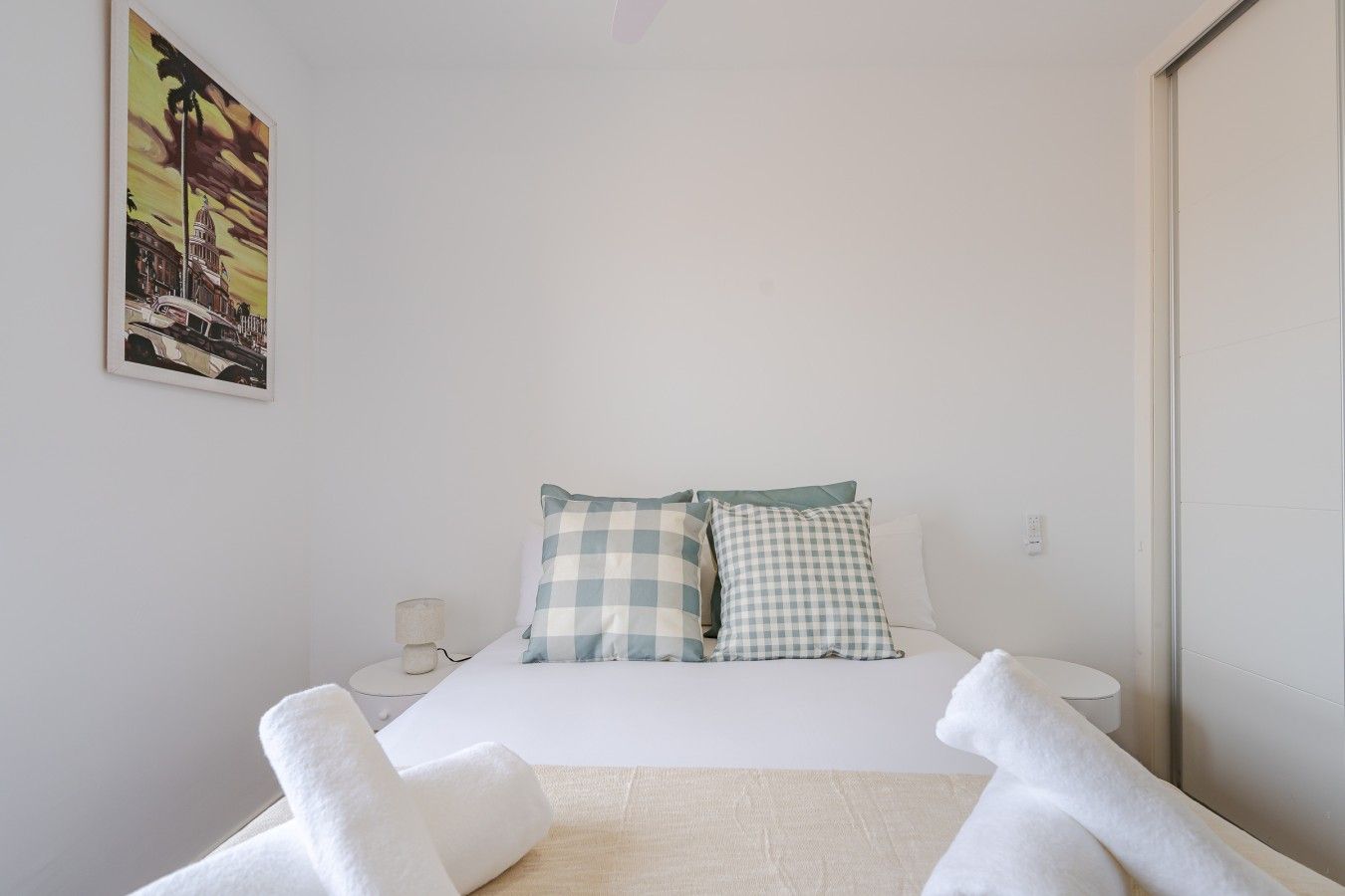 Ein Hotelzimmer mit einem Bett, karierten Kissen, einem Nachttisch, einer Lampe und einem Bild an der Wand.
