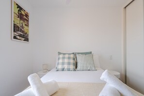 A hotel room with a bed, checkered pillows, a nightstand, a lamp, and a painting on the wall. - Apartment in downtown Getafe (Getafe)