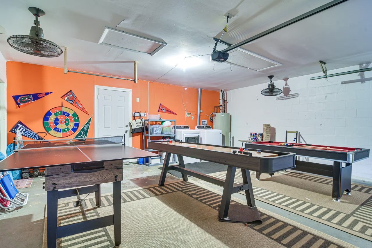 A recreational room with a ping pong table, pool table, and various sports equipment.