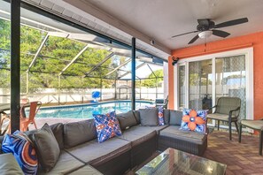 An outdoor seating area with a pool view, a ceiling fan, and a glass table. - Largo Oasis w/ Pool & Grill~6 Mi to Beach! (Largo)