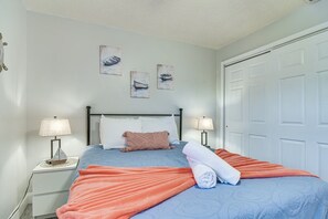 A bedroom with a bed, two bedside tables with lamps, a white door, and wall art. - Largo Oasis w/ Pool & Grill~6 Mi to Beach! (Largo)
